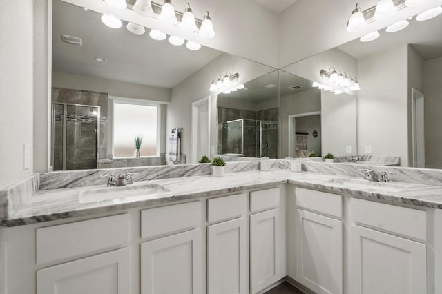 full bath with a sink, a stall shower, double vanity, and visible vents