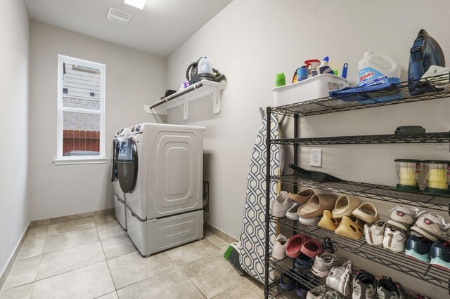 laundry room featuring laundry area, baseboards, light tile patterned flooring, and washer and dryer