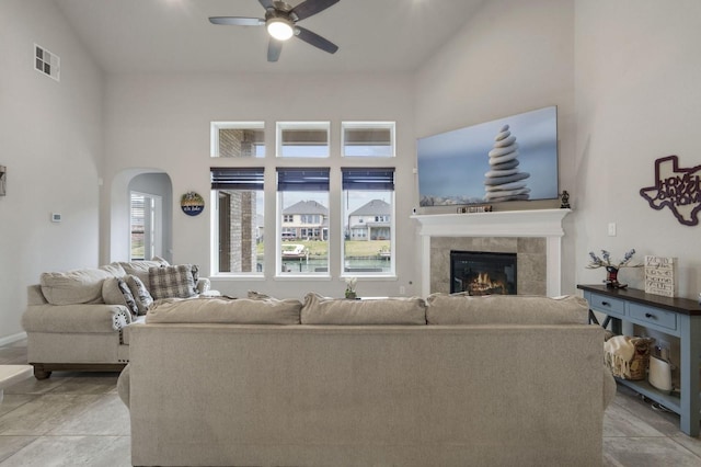living room with visible vents, a fireplace, a high ceiling, arched walkways, and a ceiling fan