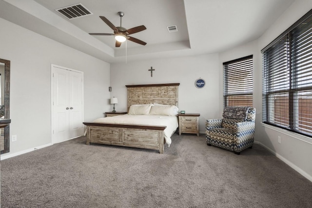 carpeted bedroom with a raised ceiling, baseboards, ceiling fan, and visible vents