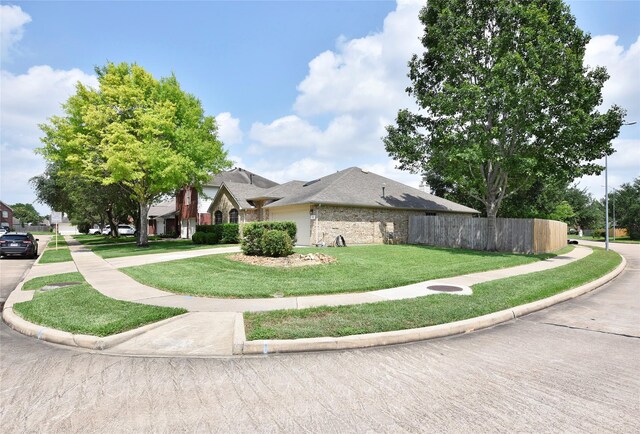 exterior space with a garage, a front lawn, fence, brick siding, and driveway
