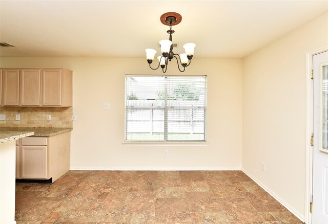 unfurnished dining area with visible vents, baseboards, a chandelier, and stone finish floor