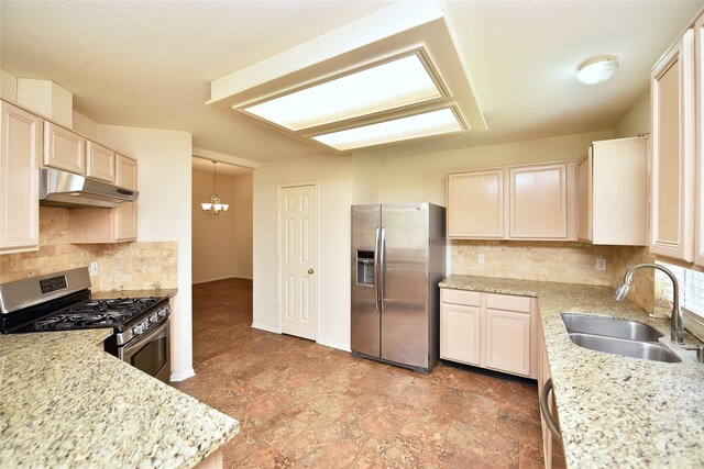 kitchen featuring decorative backsplash, under cabinet range hood, light stone counters, a sink, and stainless steel appliances