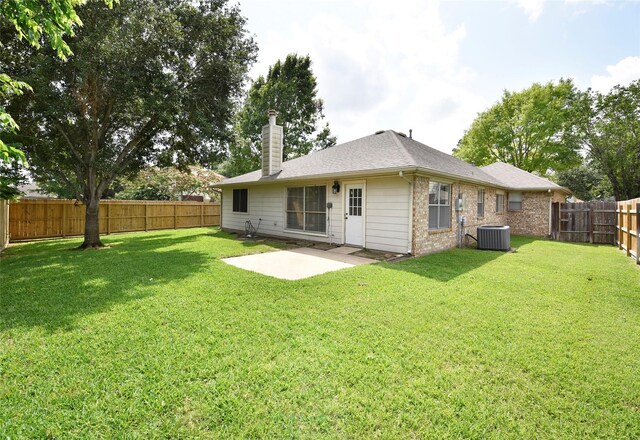 back of house featuring a patio, a fenced backyard, a chimney, a lawn, and central air condition unit