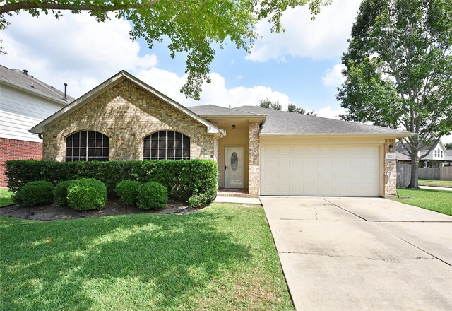 ranch-style home featuring fence, an attached garage, brick siding, a front yard, and driveway