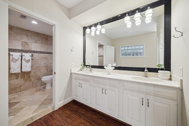 7924 Woodway Dr, Houston, TX 77063 - bathroom with tiled shower, double vanity, toilet, and wood finished floors