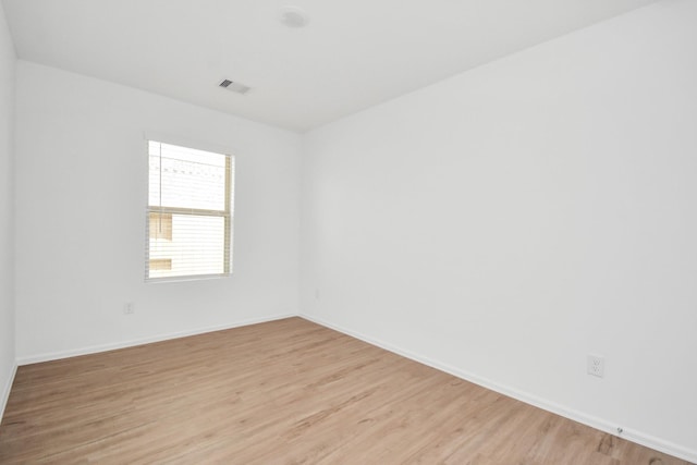 unfurnished room featuring baseboards, light wood-style flooring, and visible vents