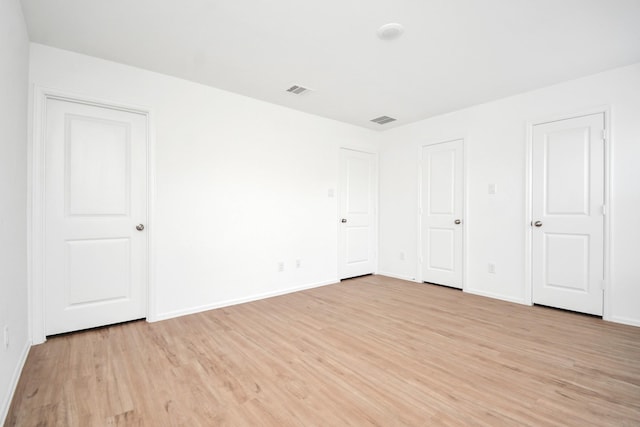 unfurnished bedroom featuring baseboards, light wood-style flooring, and visible vents