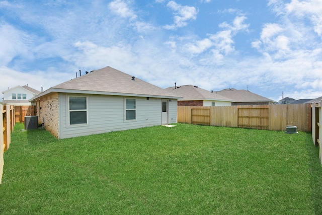 back of property with a fenced backyard, a yard, and central AC unit