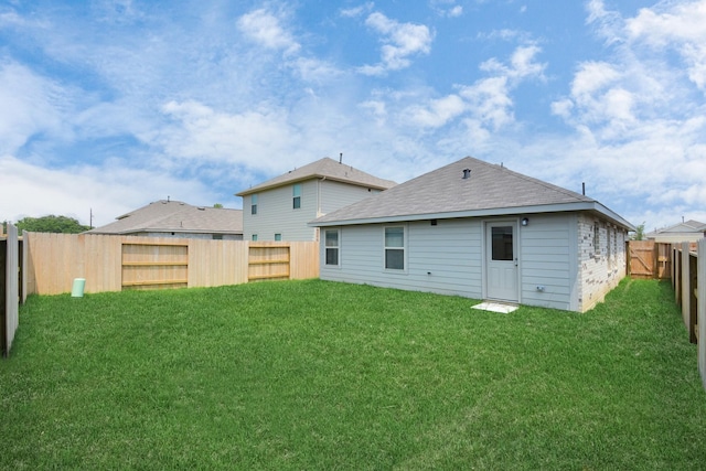 back of house with a yard and a fenced backyard