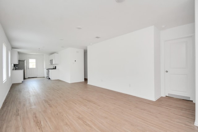 unfurnished living room featuring baseboards and light wood-style flooring