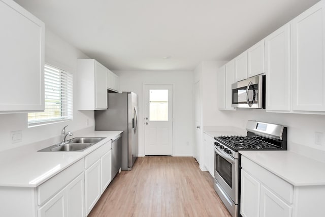 kitchen with stainless steel appliances, plenty of natural light, a sink, and light wood-style flooring