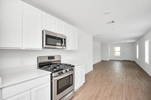 kitchen featuring visible vents, appliances with stainless steel finishes, light wood-type flooring, open floor plan, and white cabinetry