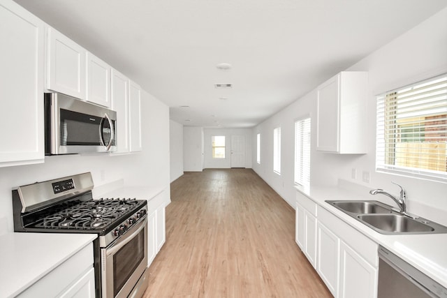 kitchen featuring light wood-style floors, a sink, light countertops, and stainless steel appliances