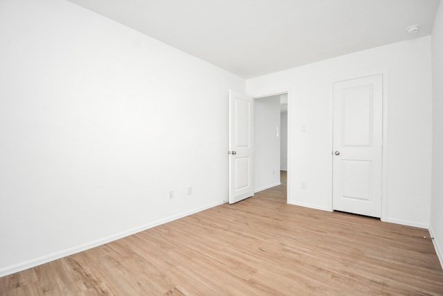 spare room with baseboards and light wood-style flooring