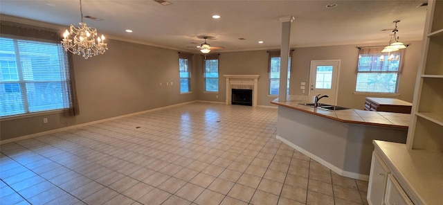 unfurnished living room featuring ornamental molding, a sink, a healthy amount of sunlight, and a fireplace