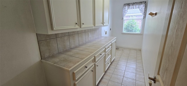 interior space with cabinet space, hookup for an electric dryer, and light tile patterned floors