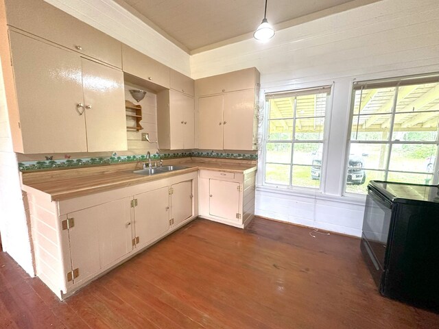 kitchen with a sink, black range with electric cooktop, hanging light fixtures, and dark wood finished floors