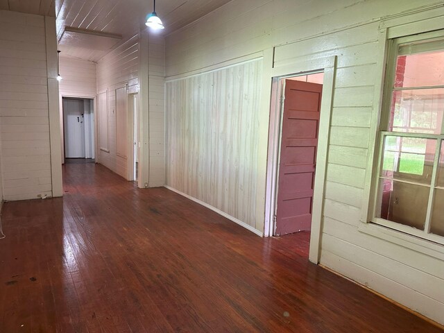 hallway featuring wood walls, dark wood-style flooring, and lofted ceiling