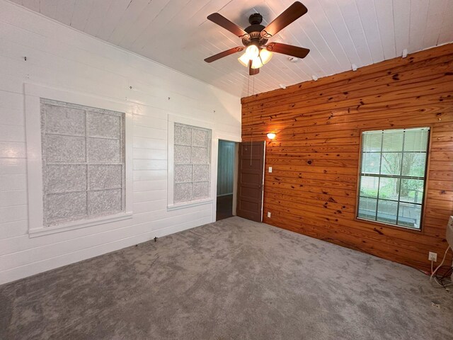 carpeted spare room with wood walls, wood ceiling, and a ceiling fan