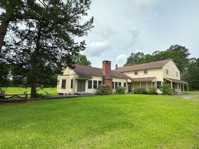 back of house with a lawn, a shingled roof, and a chimney