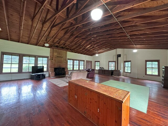 unfurnished living room featuring high vaulted ceiling, a fireplace, and dark wood-style flooring
