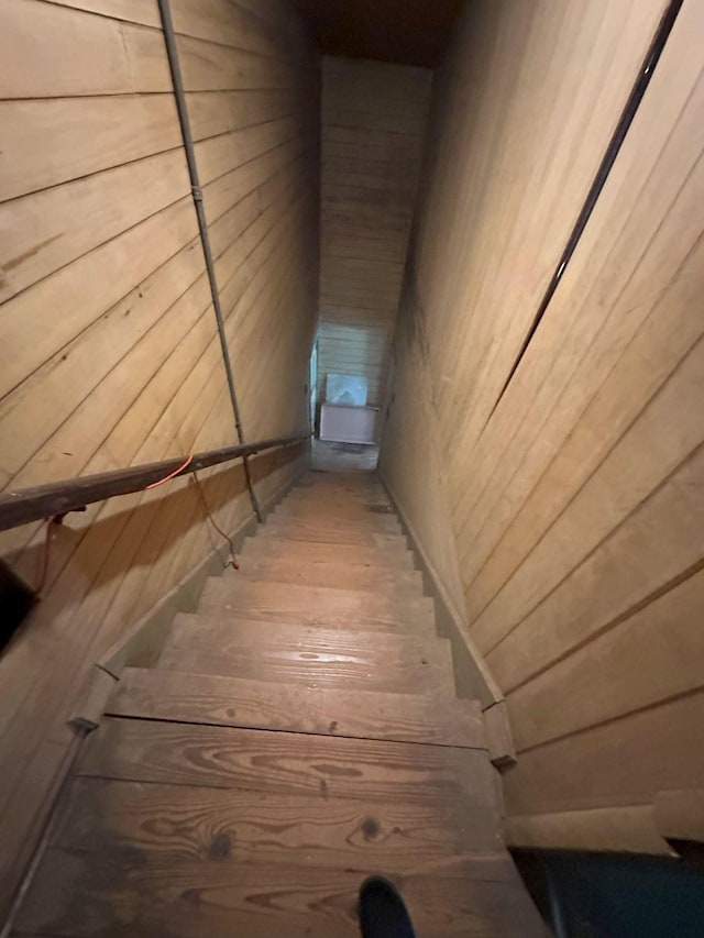 stairway featuring wood walls