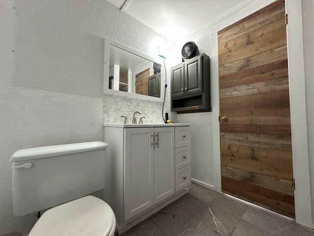 bathroom featuring backsplash, toilet, wood walls, and vanity