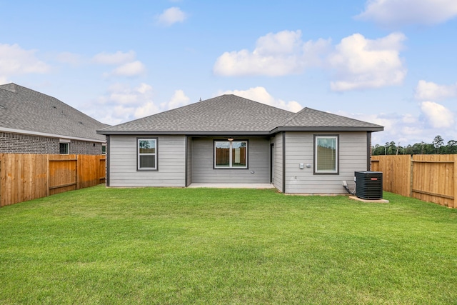 rear view of property with a fenced backyard, central air condition unit, a yard, and a shingled roof