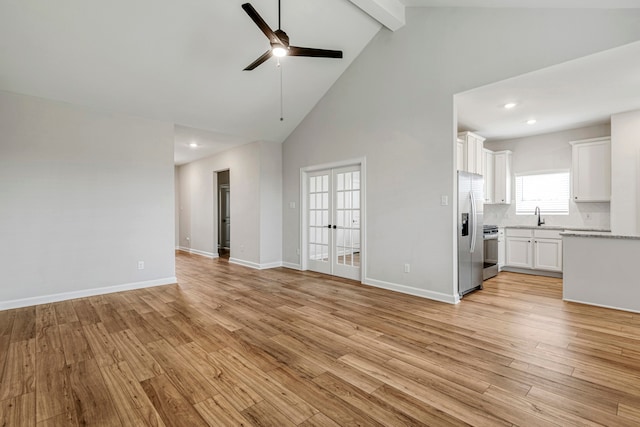 unfurnished living room with beam ceiling, high vaulted ceiling, french doors, light wood-style flooring, and a ceiling fan