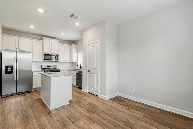 kitchen featuring a kitchen island, visible vents, appliances with stainless steel finishes, a sink, and light wood-style flooring