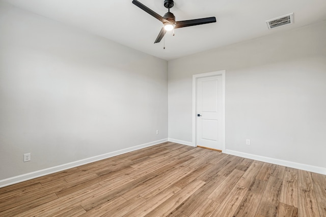 spare room with baseboards, ceiling fan, visible vents, and wood finished floors
