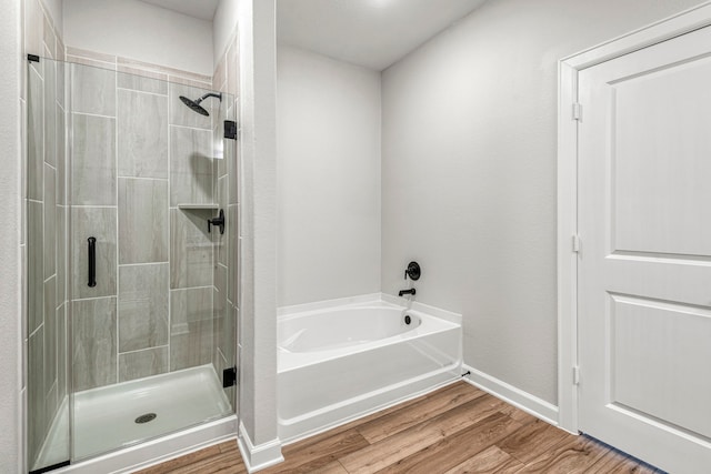 full bathroom featuring baseboards, wood finished floors, a garden tub, and a stall shower