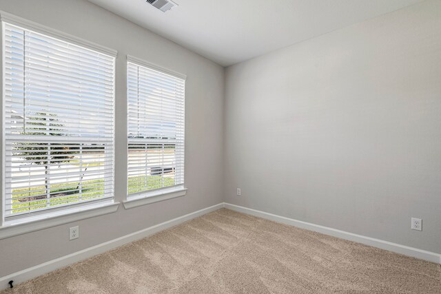 empty room with carpet floors, baseboards, visible vents, and a healthy amount of sunlight