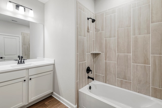 bathroom with washtub / shower combination, vanity, wood finished floors, and visible vents