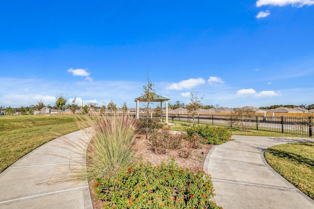 view of community featuring fence and a yard