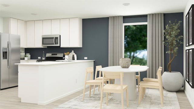 kitchen featuring a peninsula, light countertops, white cabinets, light wood-style flooring, and stainless steel appliances