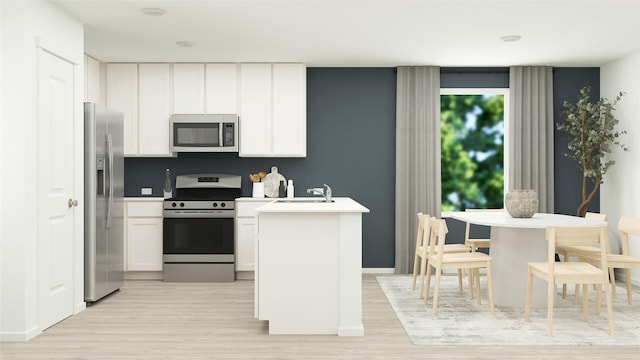 kitchen with a sink, white cabinets, stainless steel appliances, and light wood-type flooring