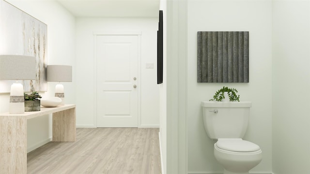 bathroom featuring baseboards, wood finished floors, and toilet