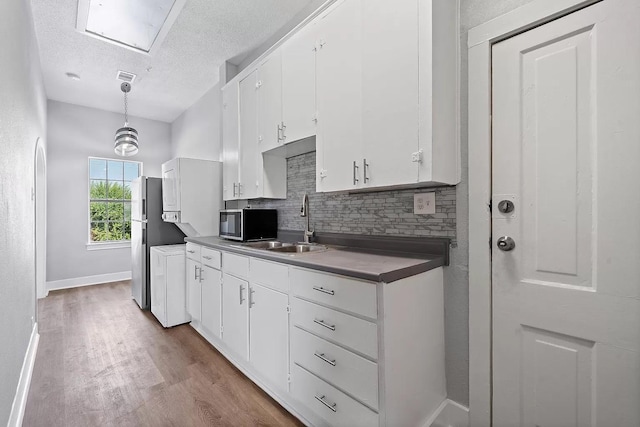 805 10th St, Galveston, TX 77550 - kitchen with a textured ceiling, appliances with stainless steel finishes, tasteful backsplash, a sink, and white cabinets