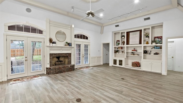 unfurnished living room featuring a ceiling fan, french doors, visible vents, wainscoting, and light wood-style floors