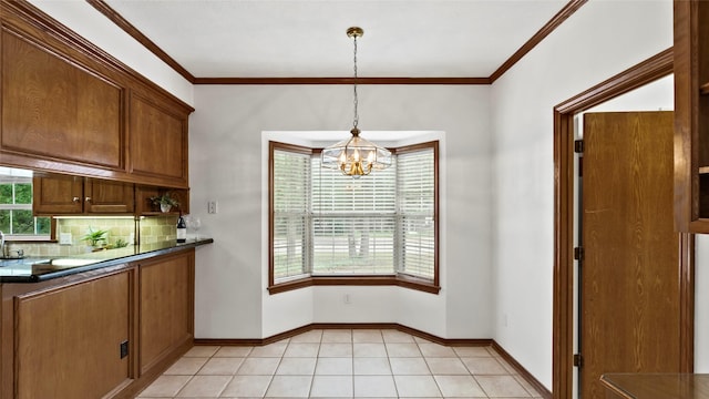 kitchen featuring dark countertops, brown cabinets, backsplash, a notable chandelier, and hanging light fixtures