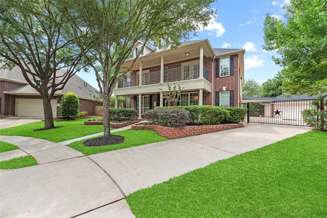 view of front of house featuring a front yard, a gate, brick siding, a balcony, and concrete driveway