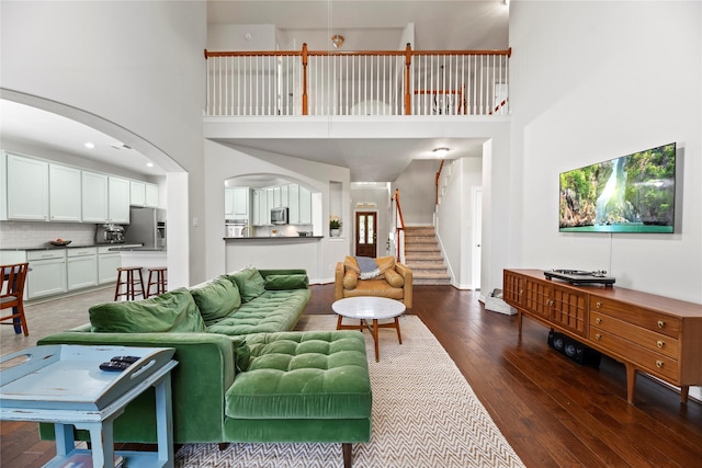 living area with wood-type flooring, arched walkways, and a high ceiling