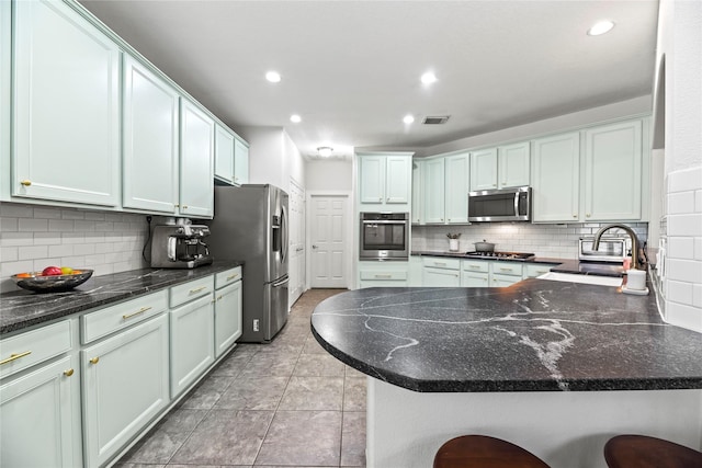 kitchen featuring decorative backsplash, visible vents, a sink, a peninsula, and stainless steel appliances