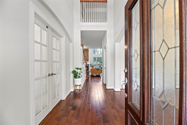 foyer entrance featuring baseboards, dark wood-style floors, and a high ceiling