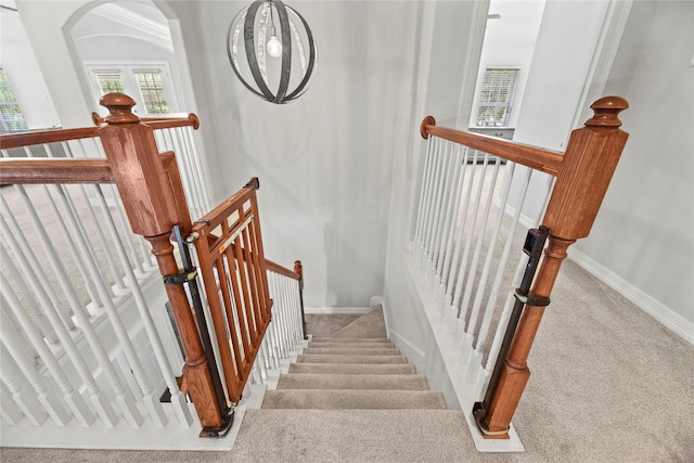 stairway with carpet floors, arched walkways, and baseboards