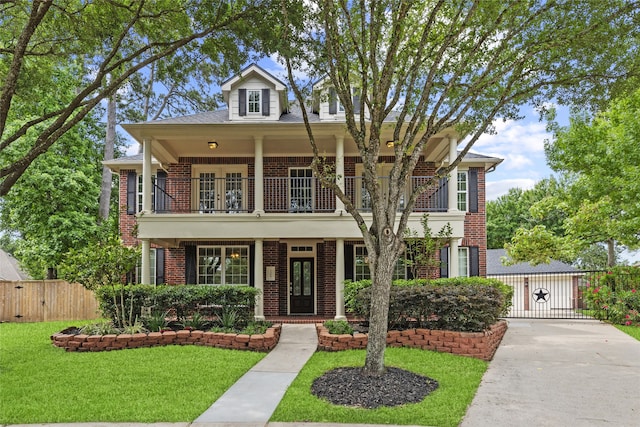 view of front facade with a gate, a front lawn, brick siding, and a balcony