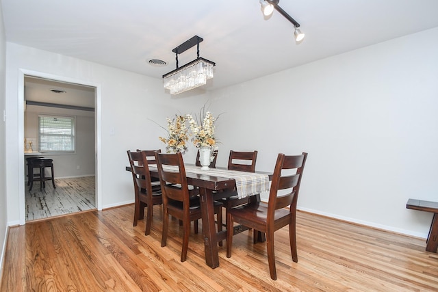 dining space featuring a notable chandelier, baseboards, visible vents, and light wood-type flooring