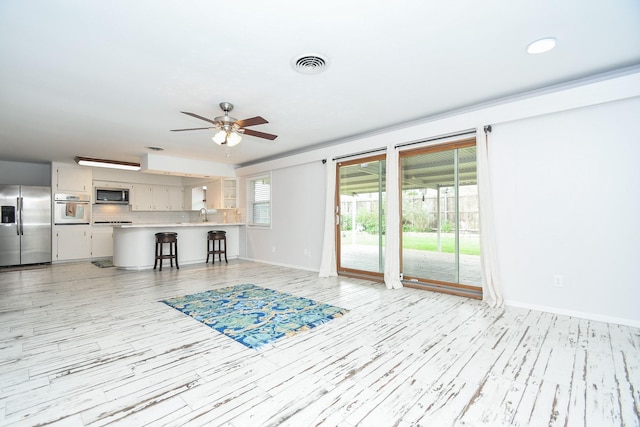 living room with light wood-style floors, baseboards, a ceiling fan, and visible vents